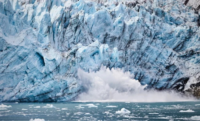 Towering Alaska glaciers calving into icy water along a cruise route.