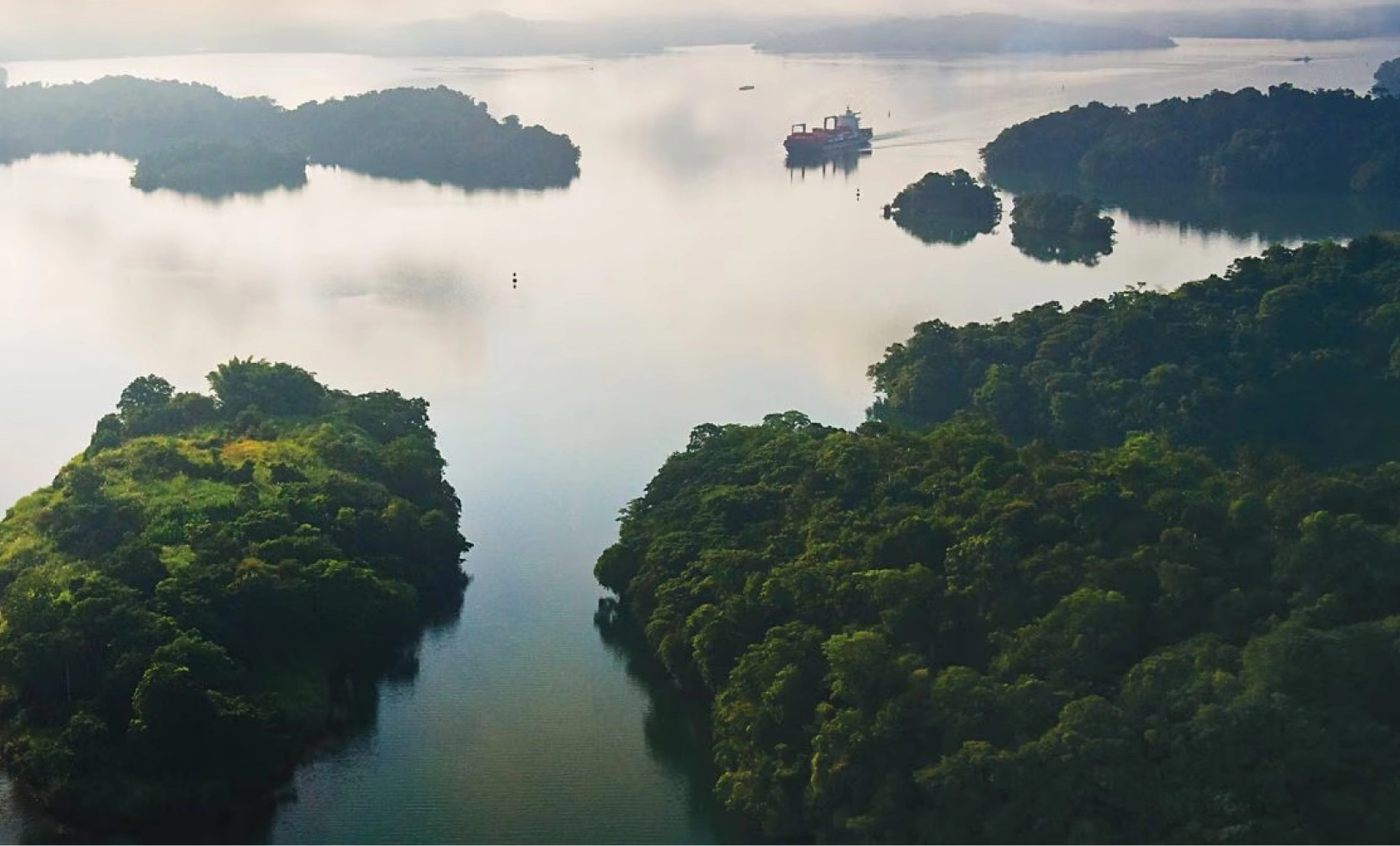 An aerial perspective of forested islands and winding waterways in Gatun Lake during a misty morning.