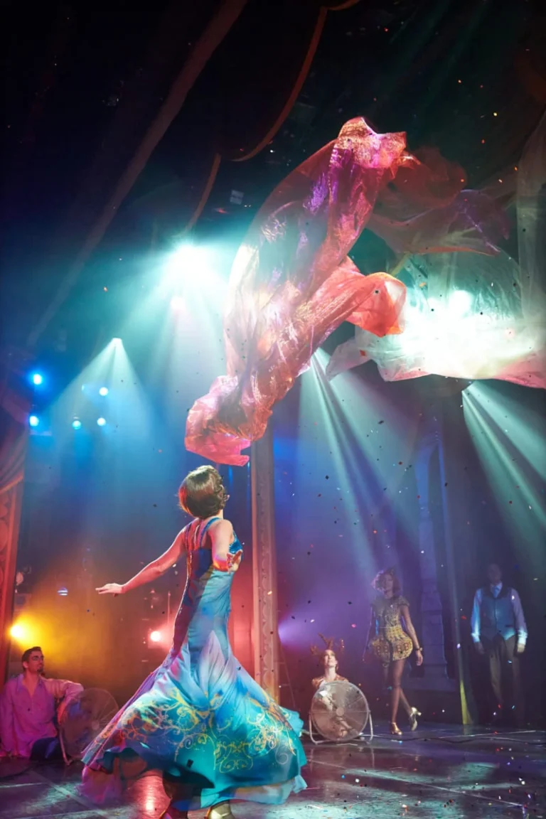 A high-energy live performance on a cruise ship stage with colorful lights and dancers.