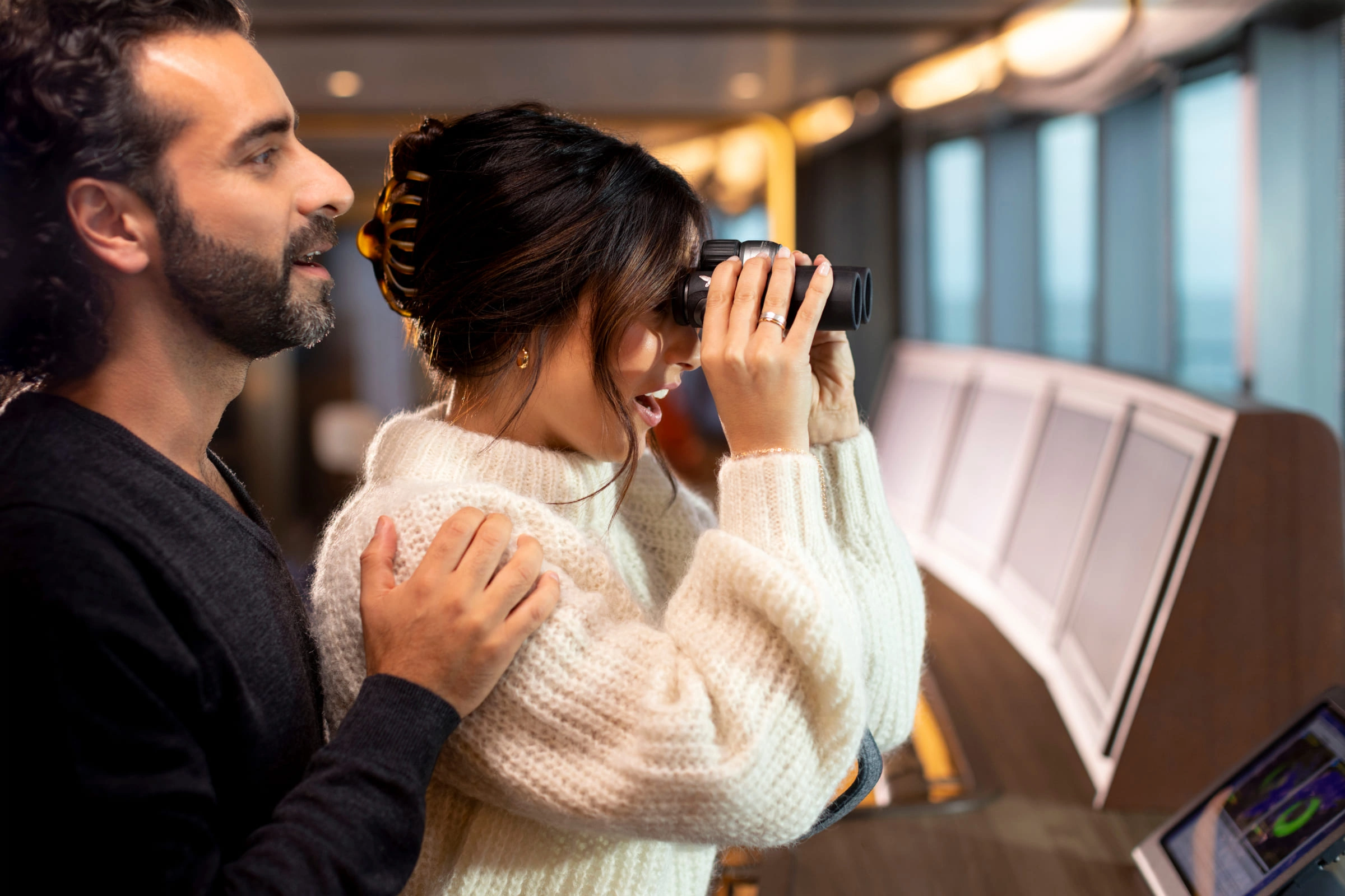 Couple looking through binoculars on a Seabourn expedition deck.