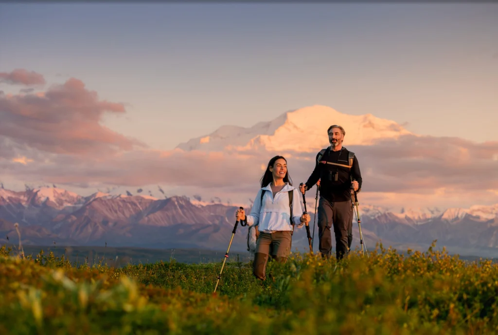 A family walking through a scenic meadow at sunset during a cruise land tour.
