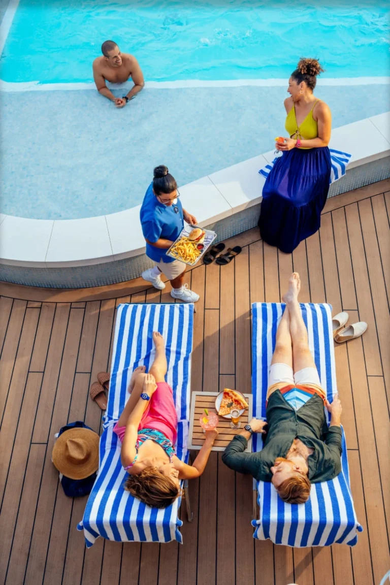 Guests relaxing on lounge chairs by a sparkling pool on the top deck.
