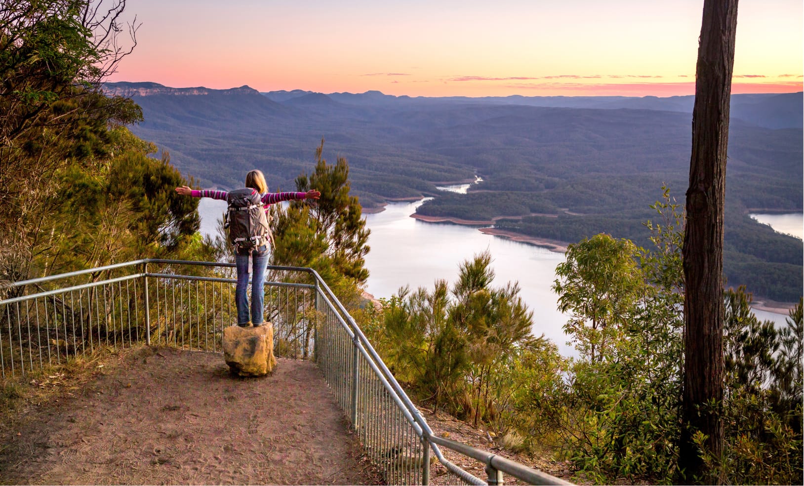 Traveler overlooking a scenic river canyon from a mountain viewpoint.