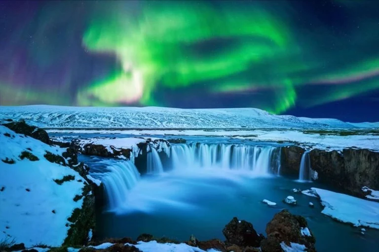 Iceland cruise destination featuring Northern Lights above waterfalls and dramatic landscapes