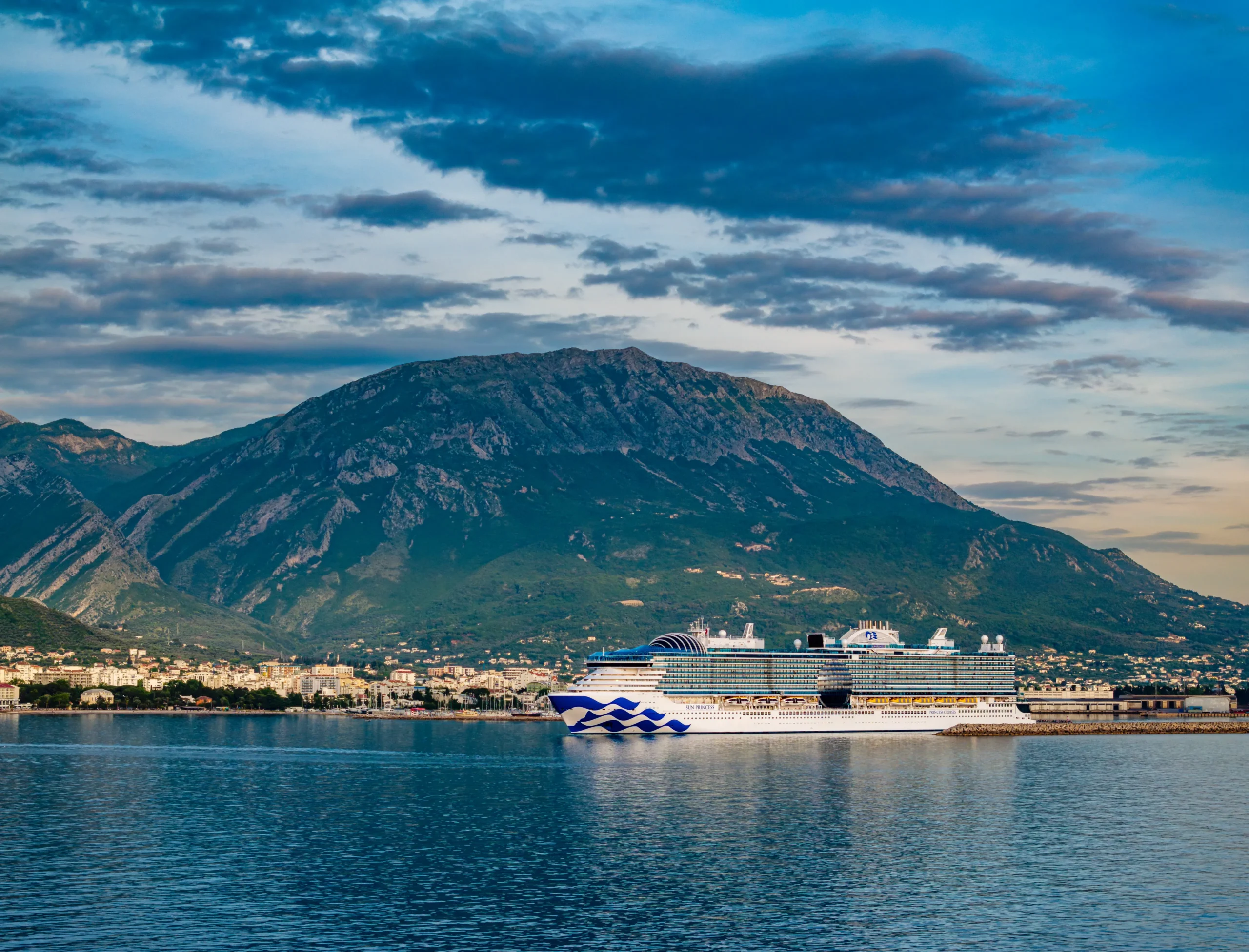 Expedition cruise ship anchored in a remote destination surrounded by mountains, highlighting the adventure side of Mainstream Cruise vs Expedition Cruise.