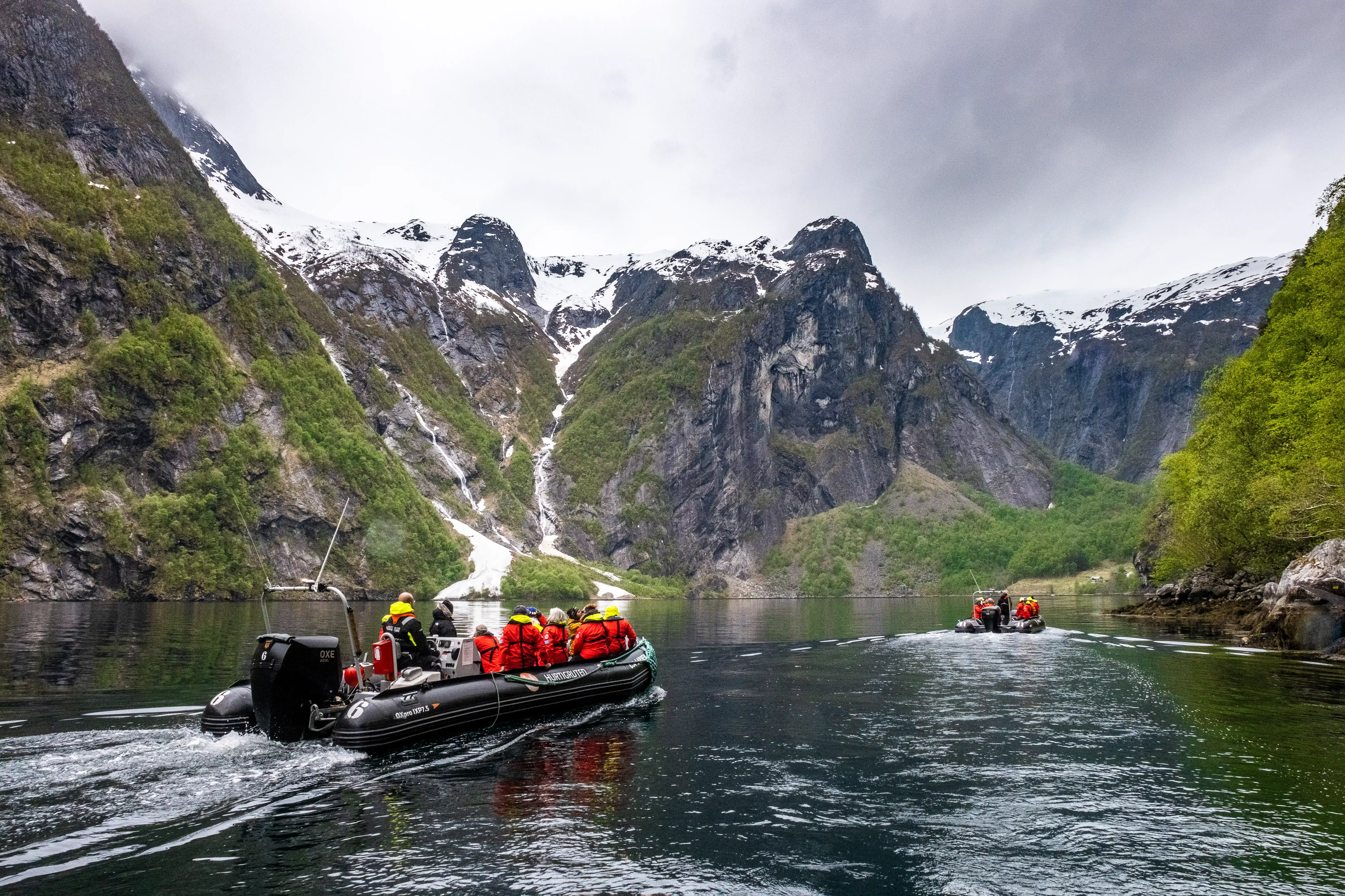 Zodiac boat carrying cruise passengers through a scenic mountain fjord during a guided shore excursion.