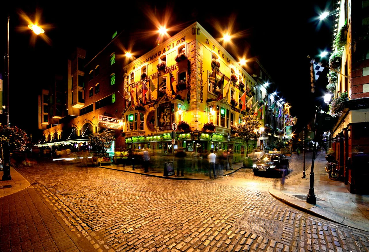 Vibrant night view of The Oliver St. John Gogarty pub in Dublin’s Temple Bar district, featuring illuminated cobblestone streets, historic Irish architecture, and crowds enjoying Dublin nightlife.