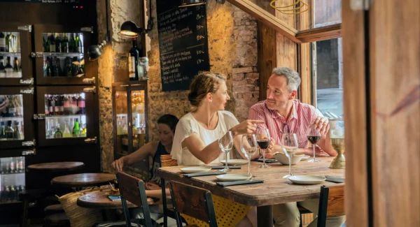 A couple sharing a romantic dinner in a rustic, wood-paneled upscale restaurant.