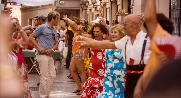A group of travelers enjoying a lively street festival or dance in a Mediterranean town.