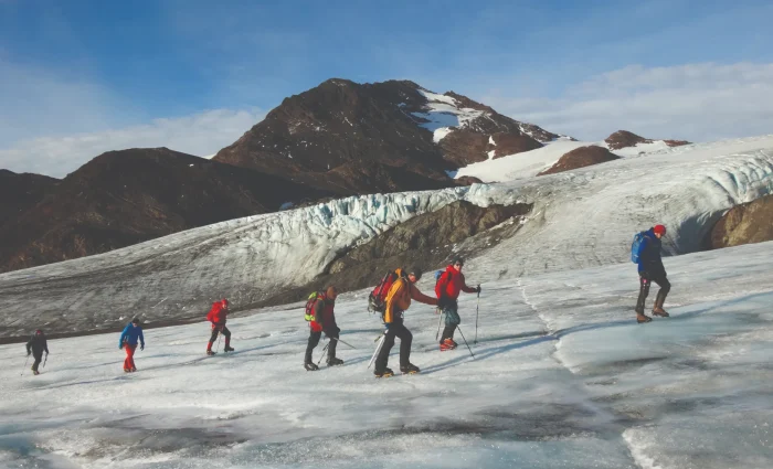 A group of people walking across a textured blue glacier surface.